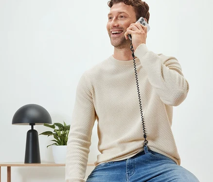 Mann sitzt und telefoniert mit Handy-Sicherheitskette.