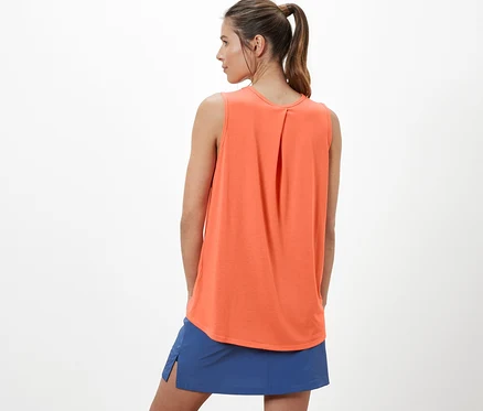 Frau trägt ein orangefarbenes Outdoor-Funktionstop und einen blauen Rock.