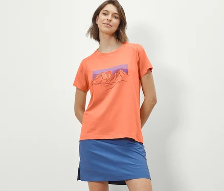 Frau trägt ein orangefarbenes T-Shirt mit Print und einen blauen Rock.