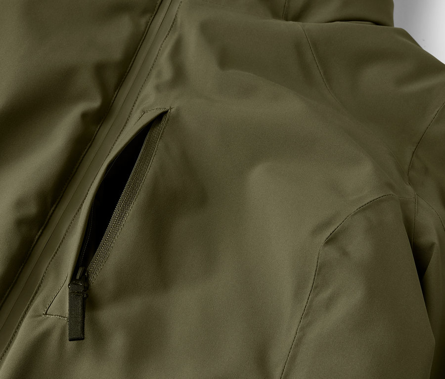 Detailaufnahme einer olivgrünen Jacke mit Reißverschlusstasche.