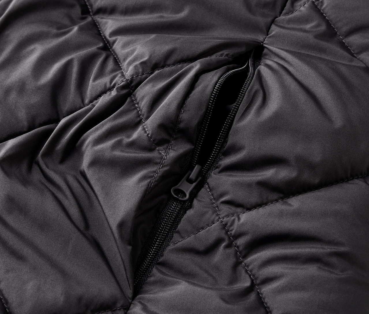 Detailaufnahme einer schwarzen Steppjacke mit Reißverschluss.