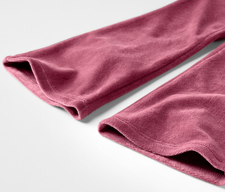 Detailaufnahme einer bordeauxfarbenen Samthose auf weißem Hintergrund.