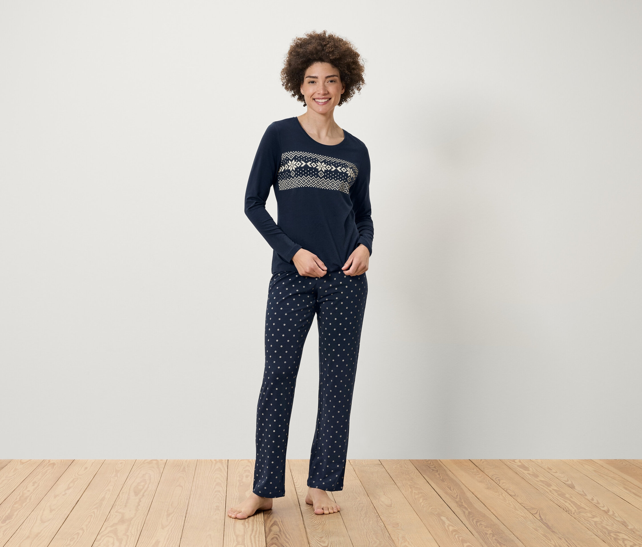 Frau steht in dunkelblauem Schlafanzug mit Muster.