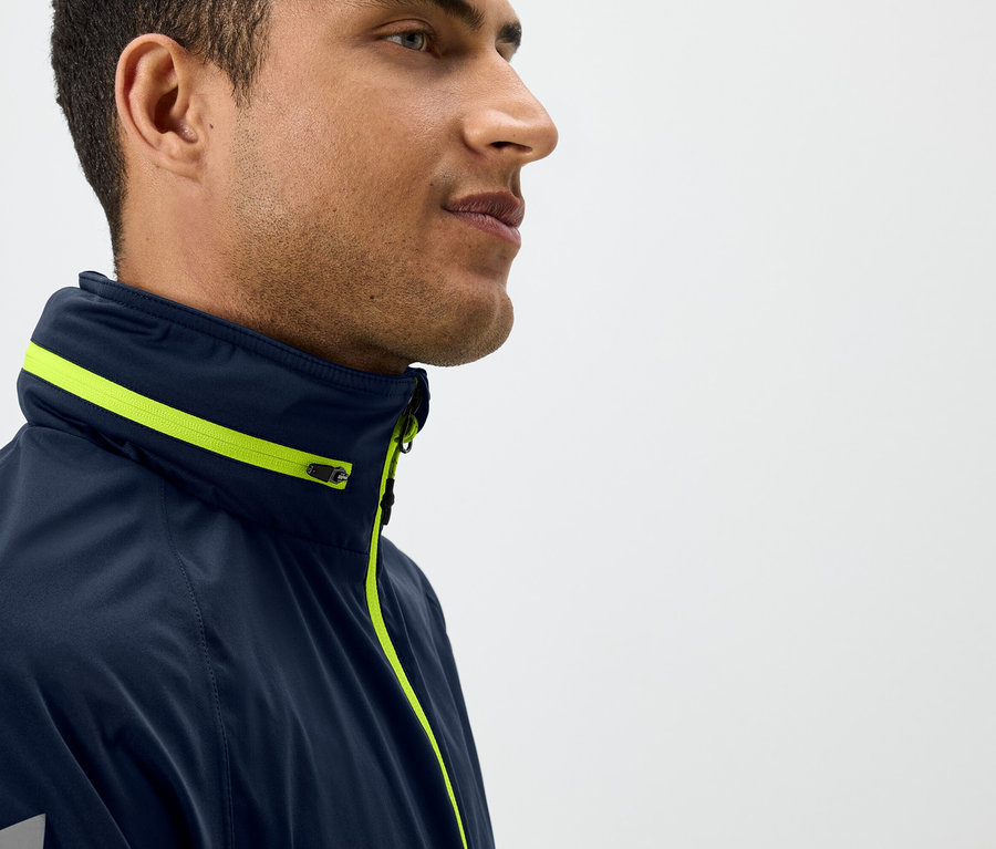 Profil eines Mannes in einer dunkelblauen Jacke mit gelben Details.