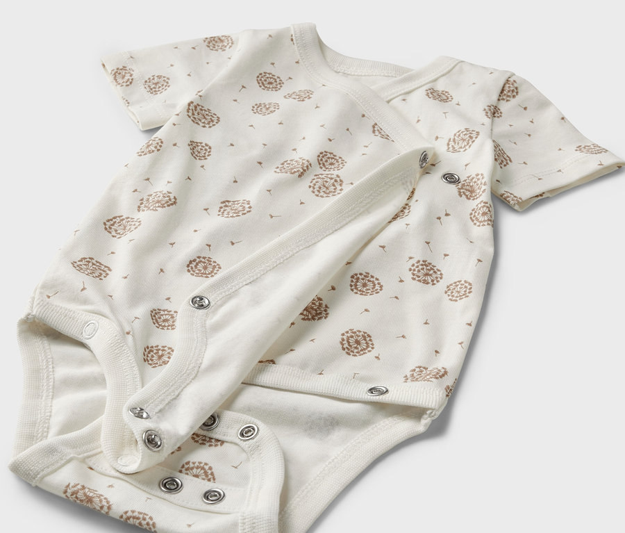 Detailansicht eines weißen Baby-Bodys mit kurzen Ärmeln und Löwenzahn-Print, 5er-Pack.