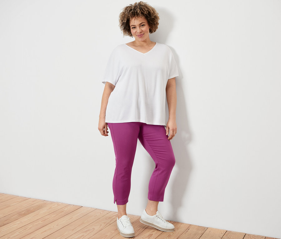 Frau posiert in 7/8-Stretchhose, berry, und strukturiertem Shirt, weiß.