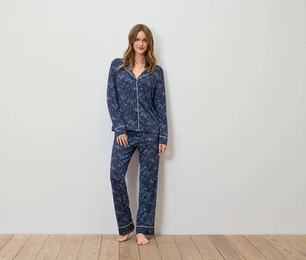 Eine Frau steht und trägt einen blauen Pyjama mit Muster.