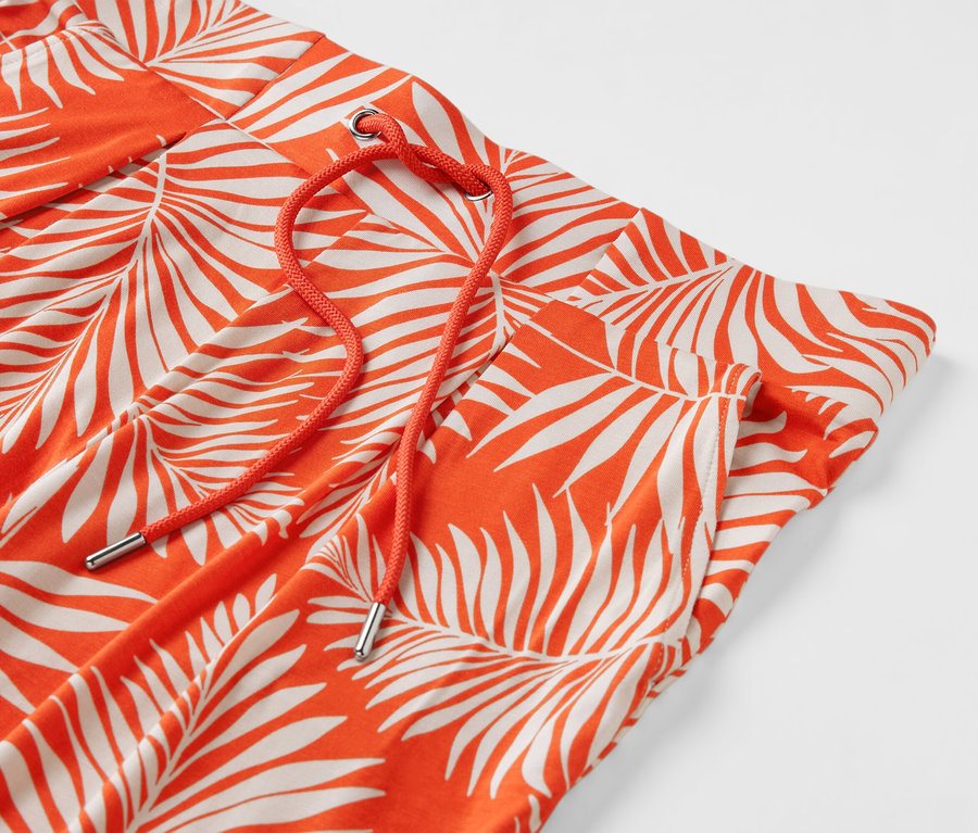 Detail einer orangefarbenen Jerseyhose mit Blattdruck und orangefarbenem Kordelzug.