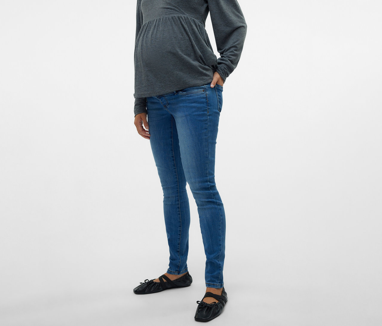 Schwangere mit grauer Bluse und MAMALICIOUS Skinnyjeans »MLMILA« mit einer Hand in der Hosentasche.