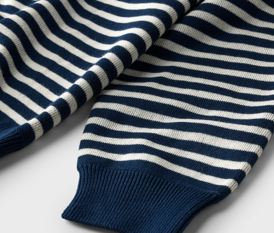 Nahaufnahme eines dunkelblauen Pullovers mit weißen Streifen und gerippten Bündchen.