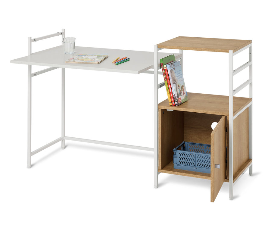 Ein weißer Schreibtisch mit einem Glas Wasser, Stiften und einem Malbuch darauf, daneben ein Regal mit Büchern und einer blauen Kiste.