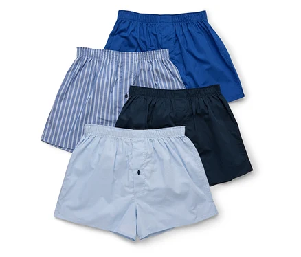 Vier Herren Boxershorts in blau, gestreift, dunkelblau und hellblau liegen übereinander.