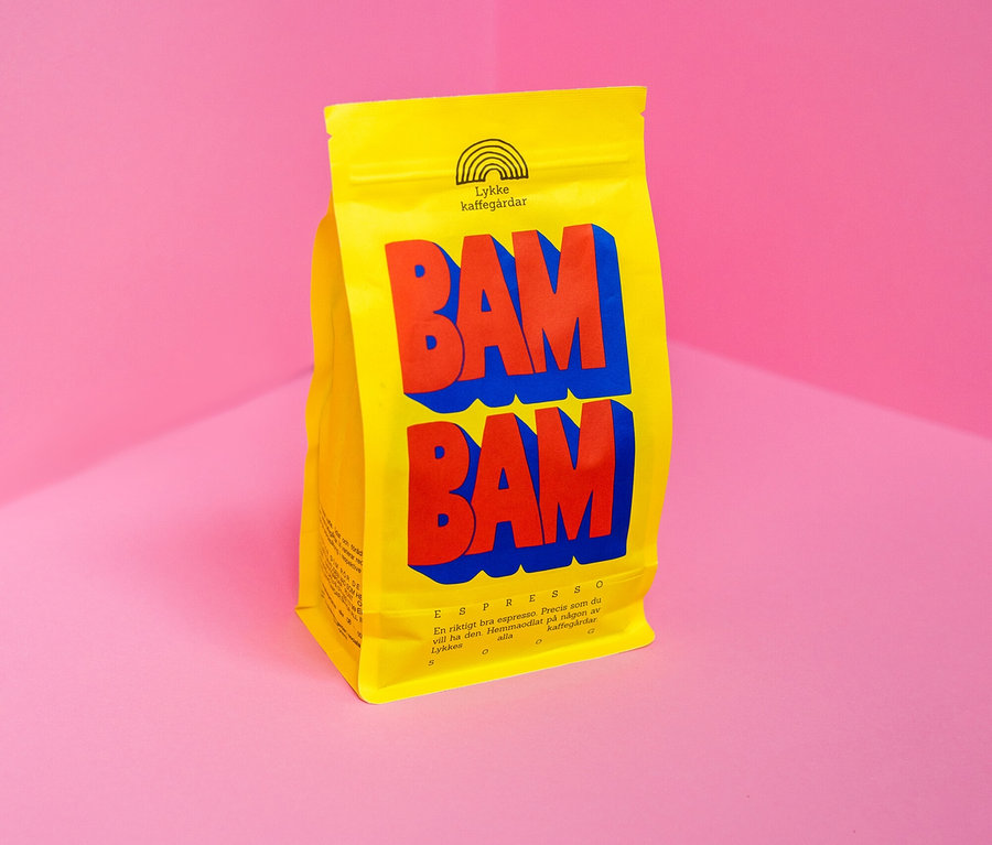 Gelbe Packung Lykke Kaffegårdar Espresso BAM BAM mit roter und blauer Schrift vor rosa Ecke.