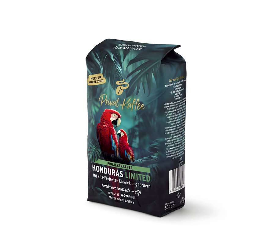 Dunkelgrüne Kaffeepackung Privat Kaffee Limited Edition Honduras mit zwei roten Aras und tropischen Blättern. Aufschrift: „Ganze Bohne, Aromafrisch, mild-aromatisch – süß, 100% Tchibo Arabica“.