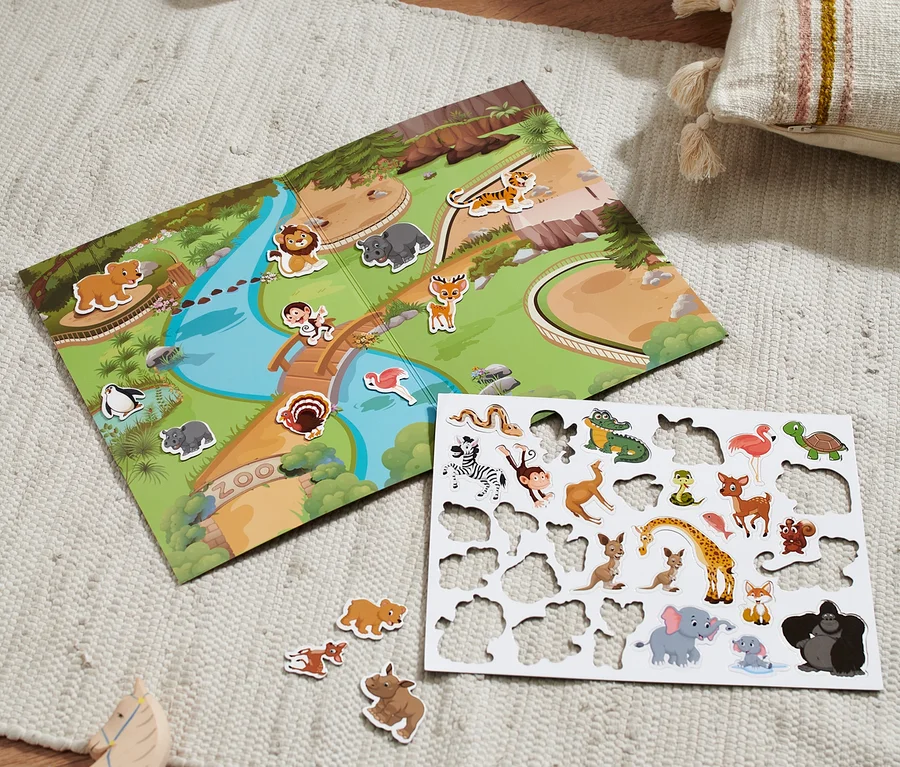 Auf einem Teppich liegt ein Zoo-Spiel und ein Bogen mit Tieraufklebern.