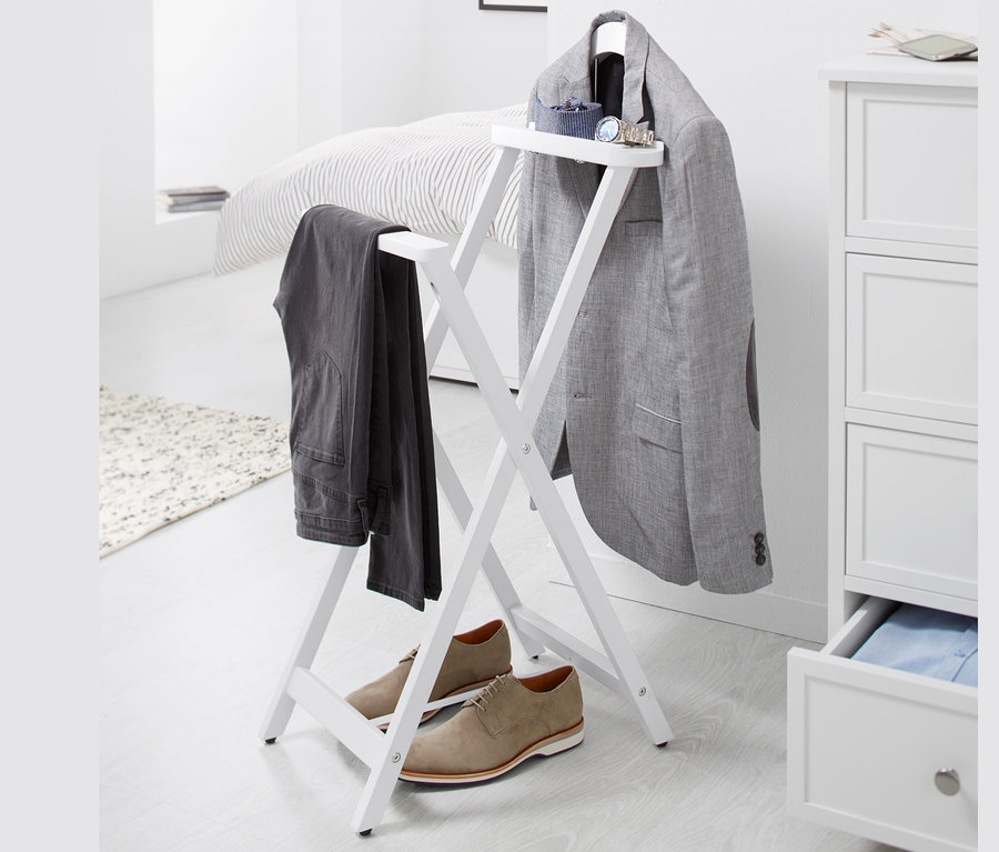 Auf einem weißen Hintergrund steht ein stummer Diener, an dem ein grauer Blazer und eine Hose hängen, darunter stehen braune Schuhe.