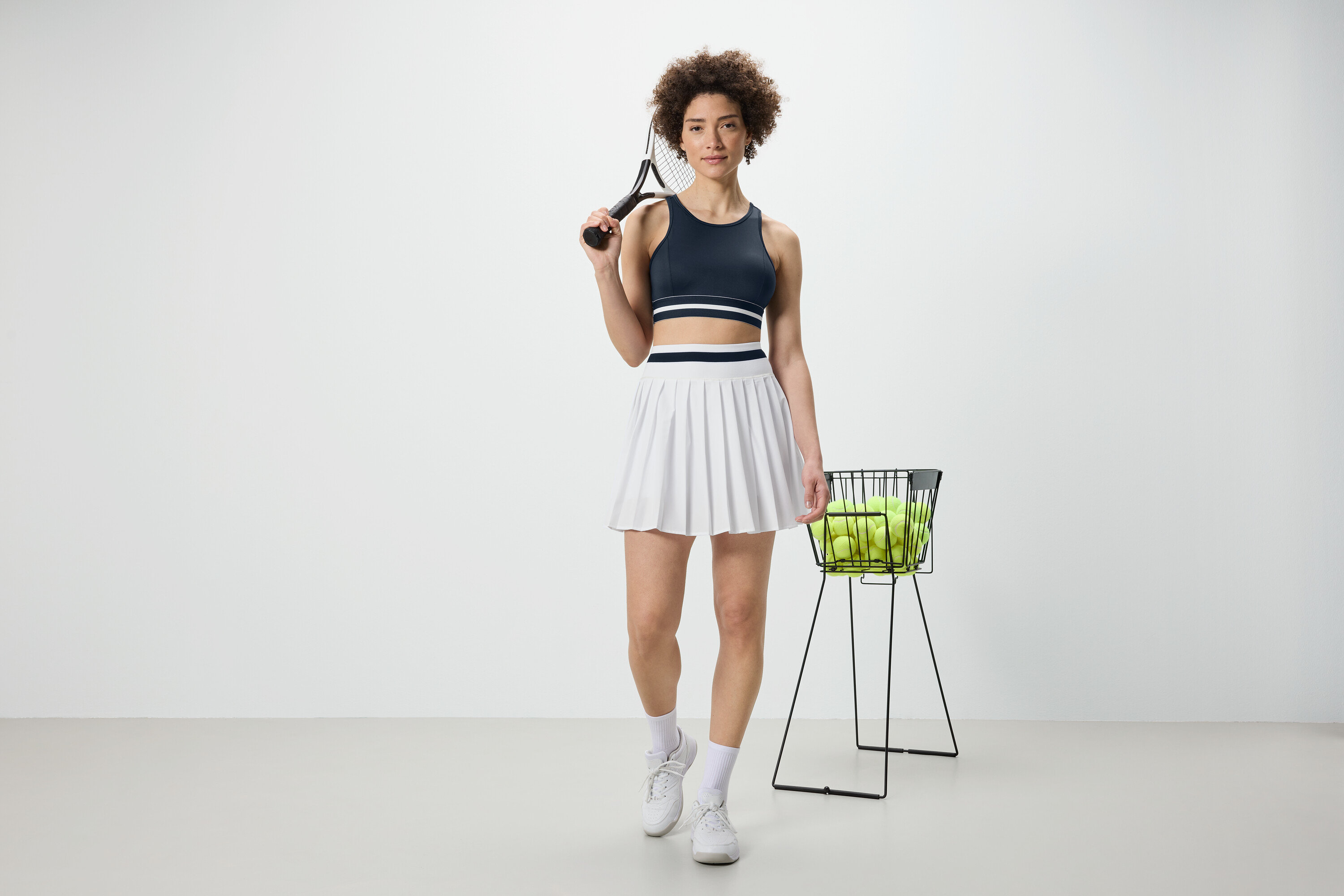 Frau hält Tennisschläger und trägt ein blaues Sport-Bustier »Crop Top«.