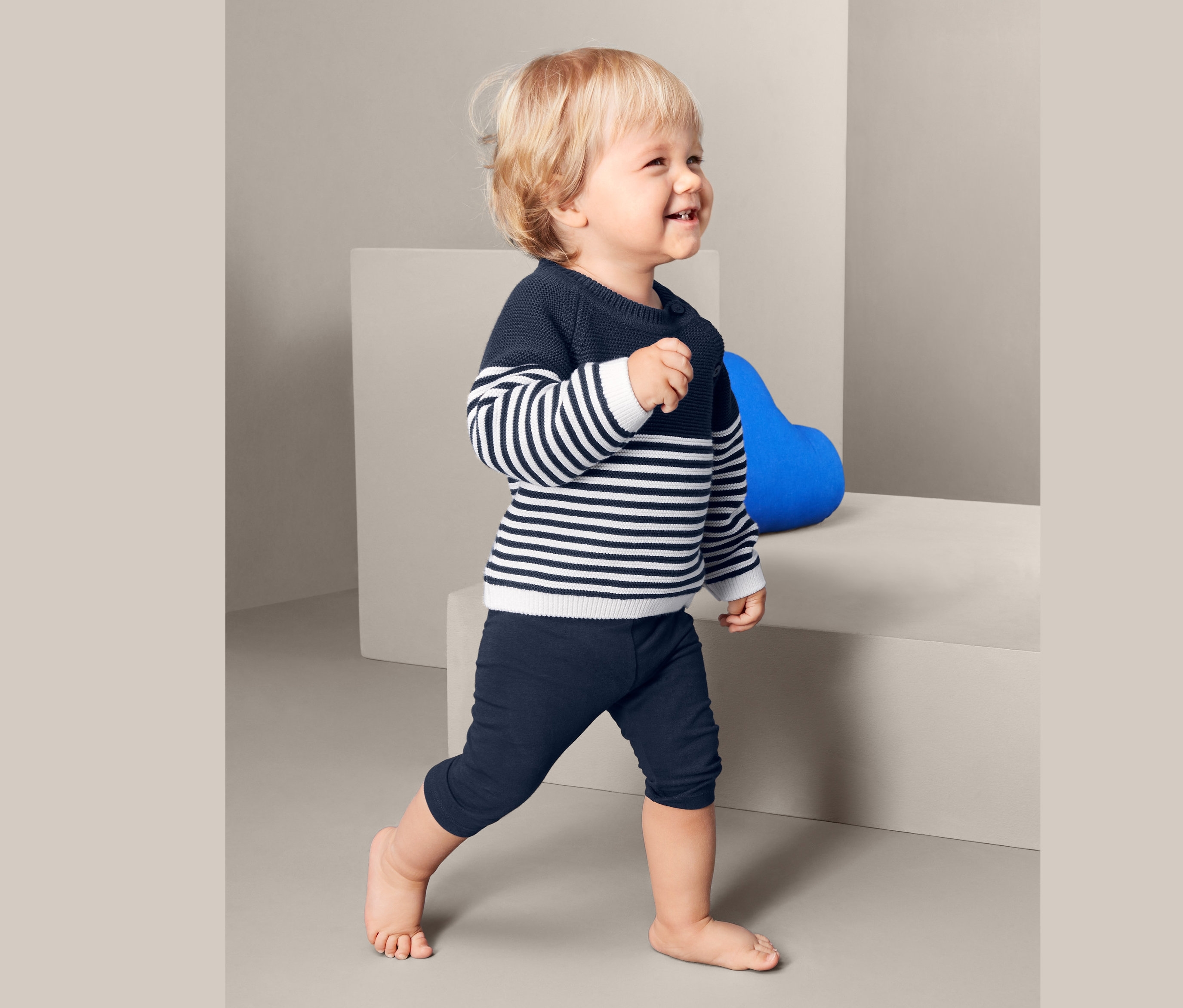 Kleinkind mit blau-weiß gestreiftem Pullover und blauen Leggings.