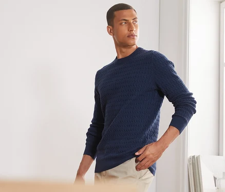Mann posiert in blau meliertem Strickpullover.