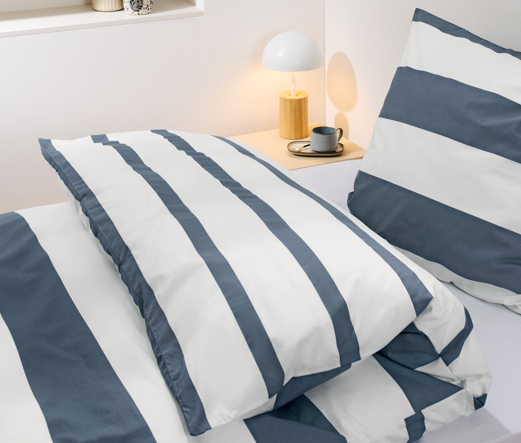 Detailansicht von gestreifter Perkal-Bettwäsche in Normalgröße auf einem Bett.