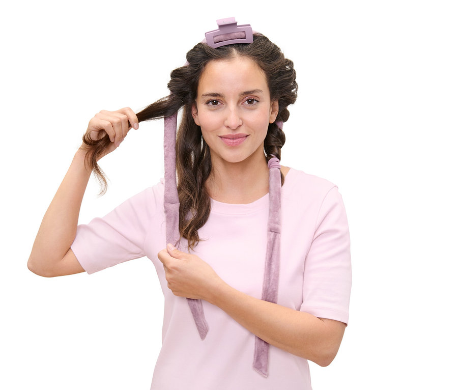 Frau wickelt Haare mit hitzefreien Lockenwicklern.