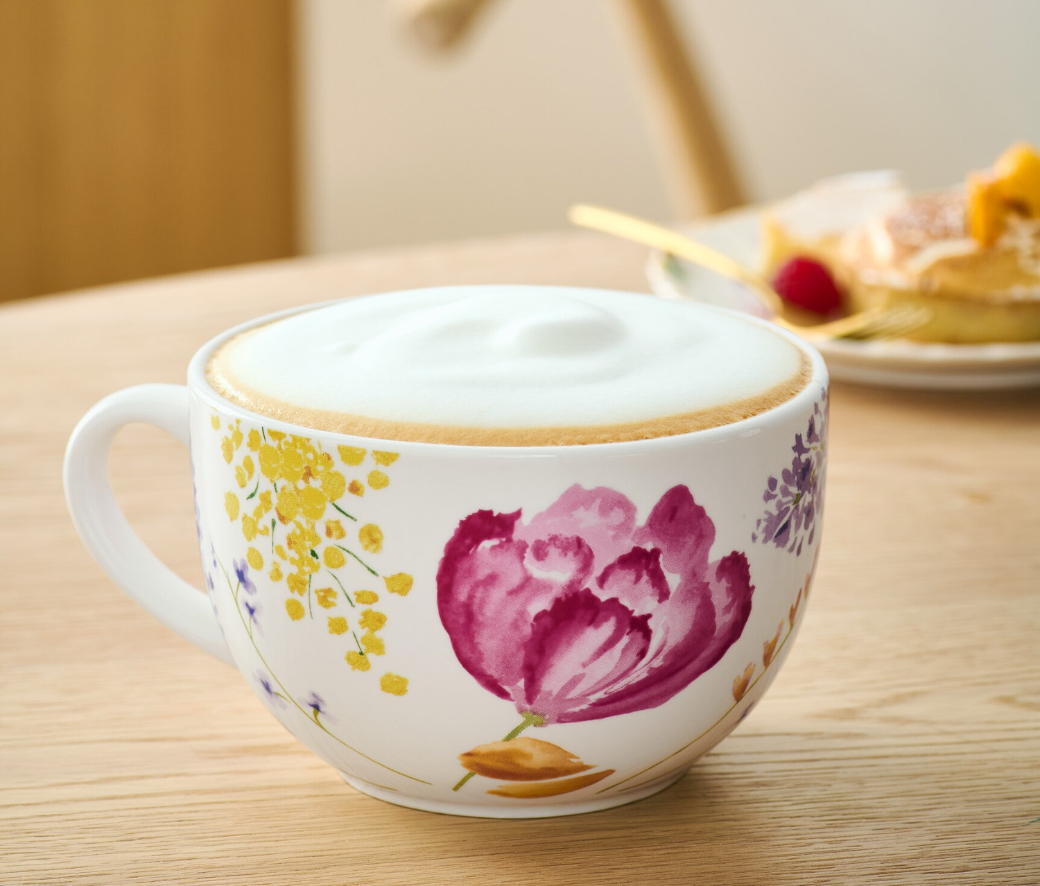 Eine Milchkaffeeschale mit Blumenmuster auf einem Tisch.