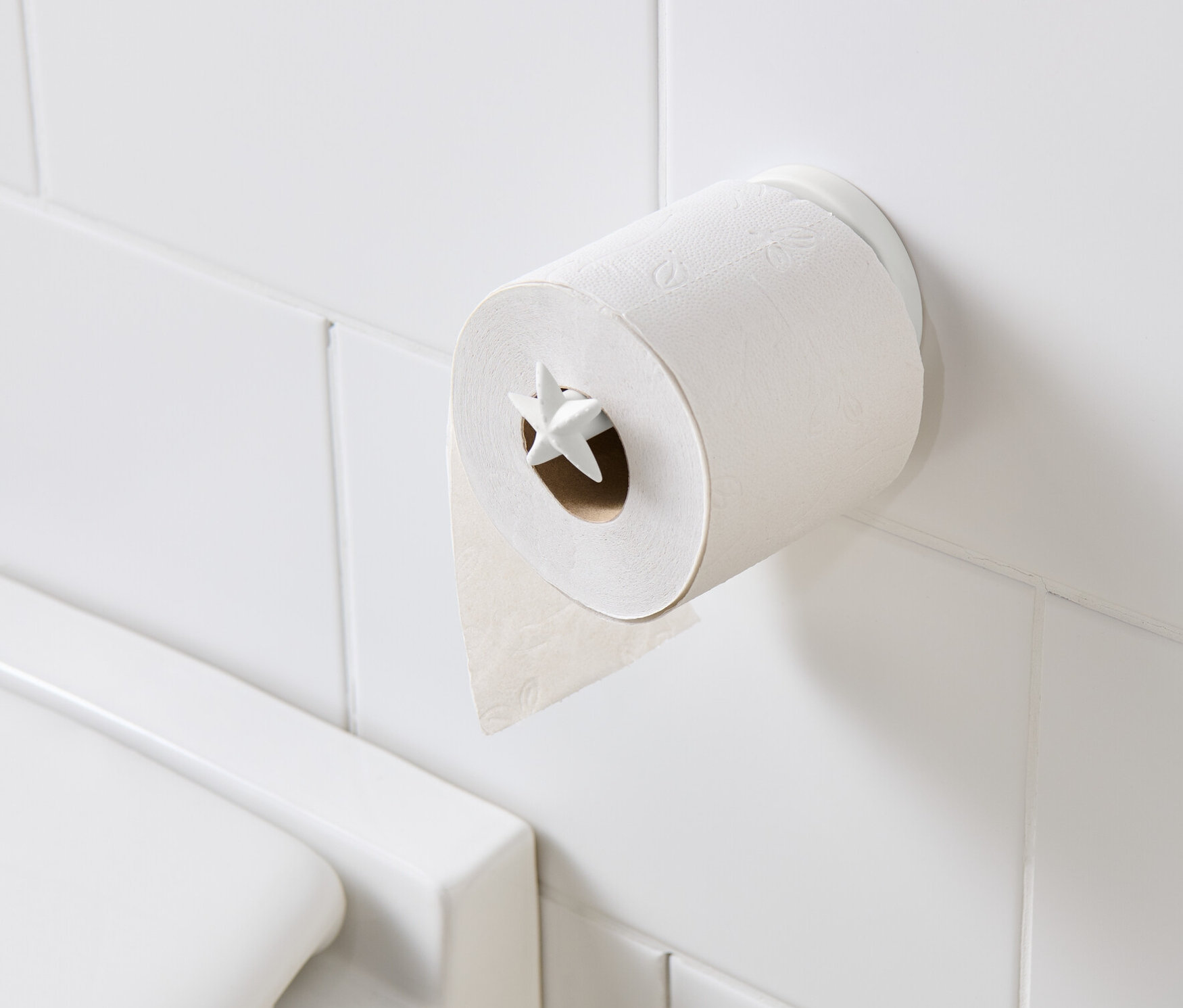 Toilettenpapierhalter mit Toilettenpapier an weißen Fliesen.