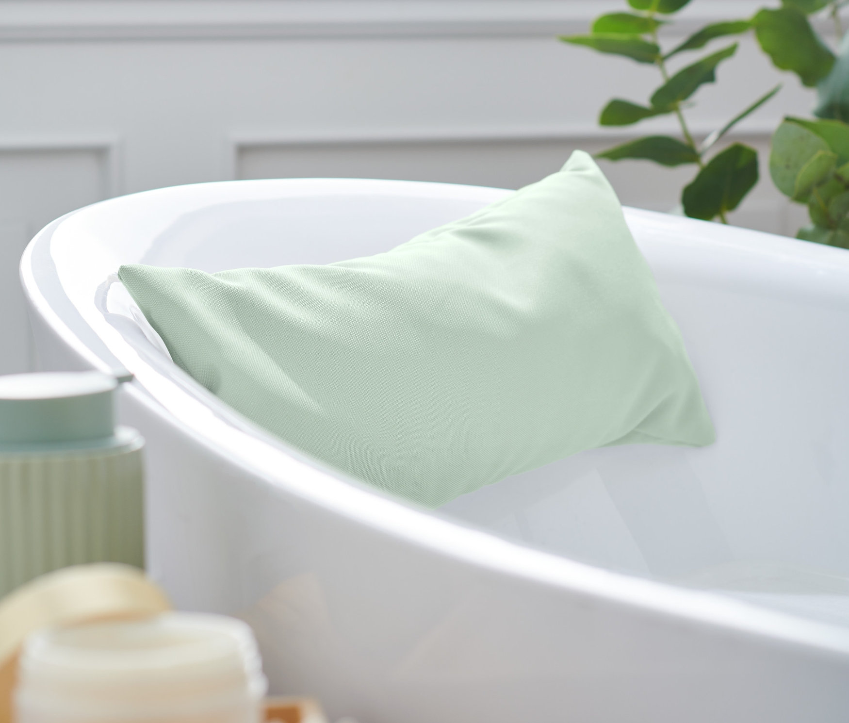Ein grünes Badewannenkissen liegt in einer weißen Badewanne.