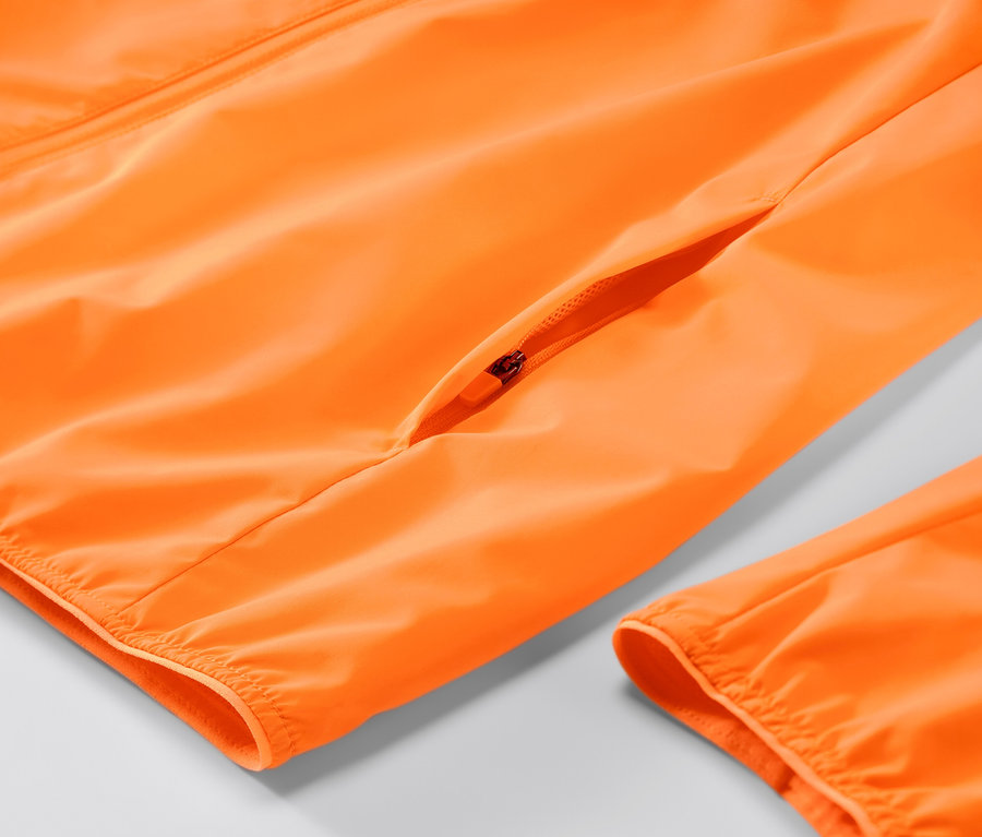 Detailansicht einer neonorangen Windprotection-Laufjacke mit Reißverschluss.