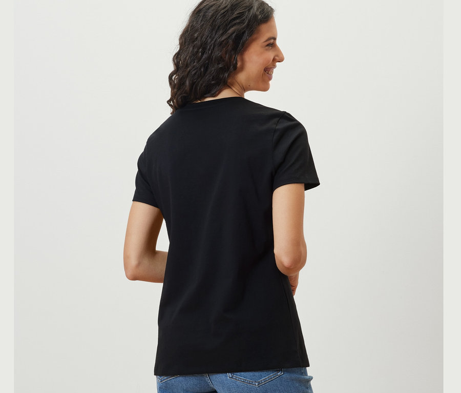 Frau schaut über die Schulter und trägt ein schwarzes Basic T-Shirt.