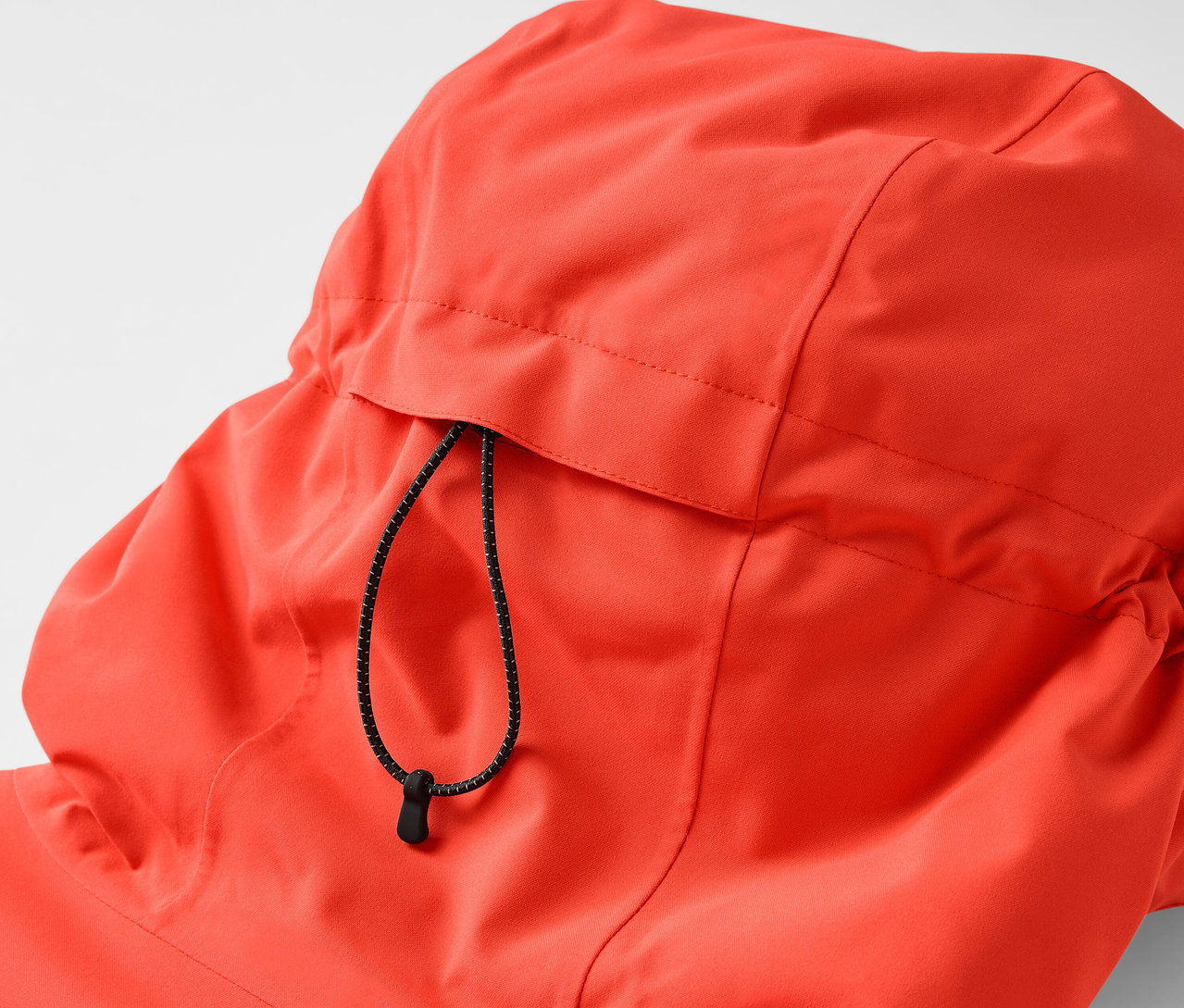 Detailansicht der Kapuze einer orangefarbenen Jacke mit Kordelzug.