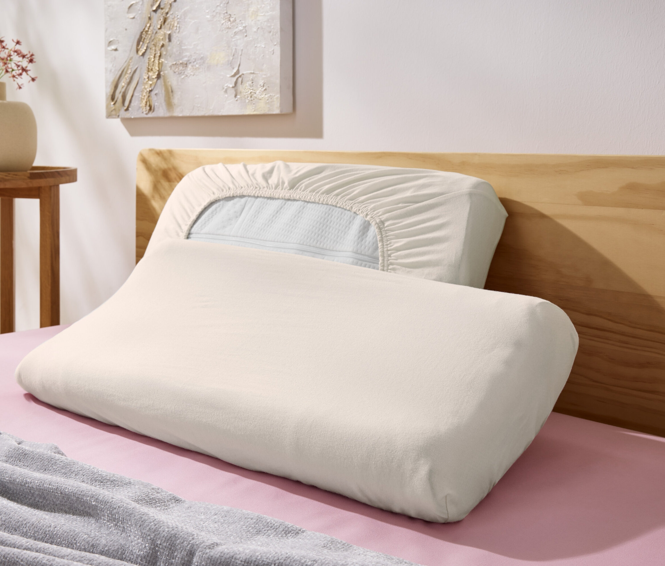 Zwei offwhite 2-Jersey-Nackenkissenbezüge liegen auf einem Bett.