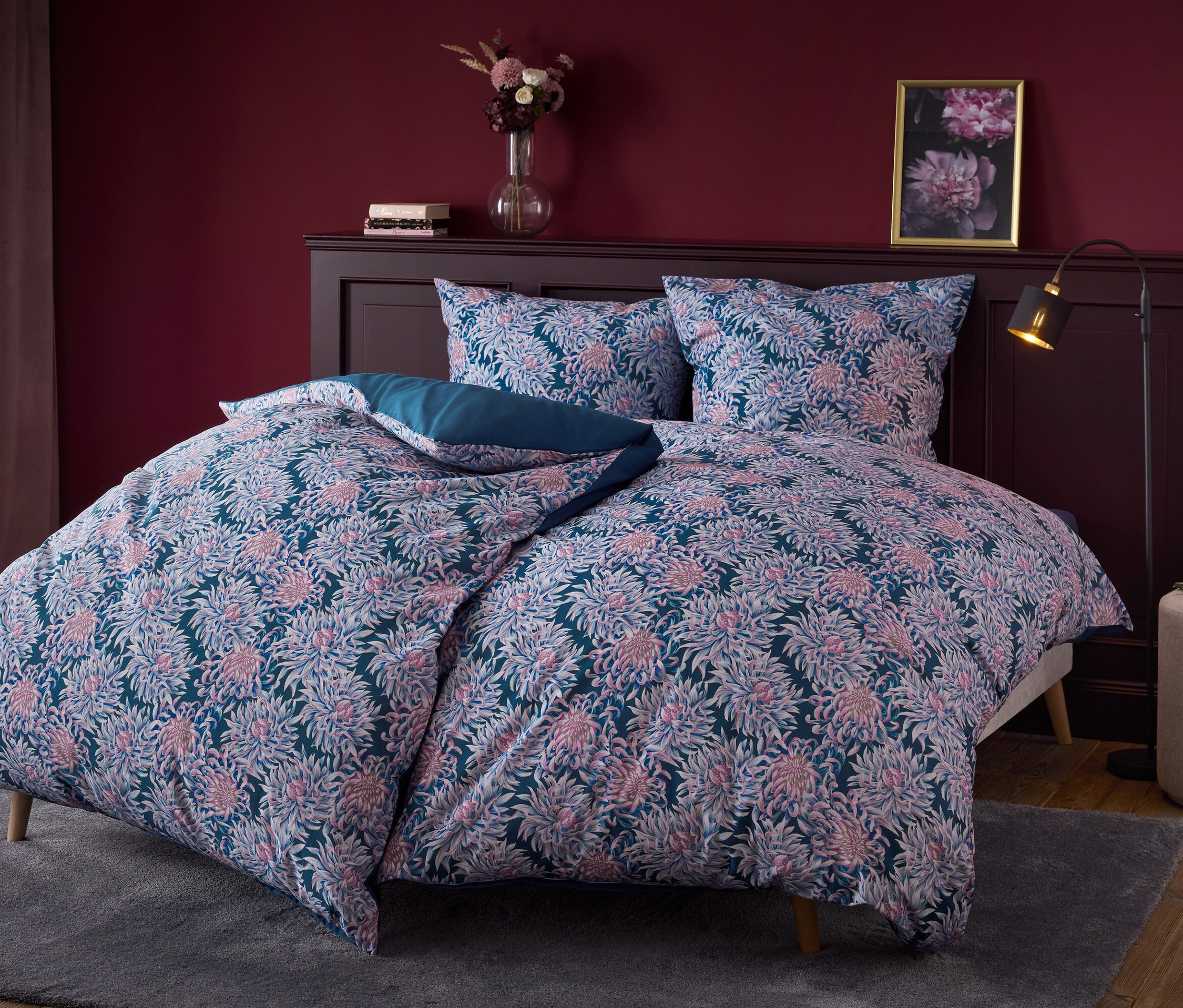 Blumige Bettwäsche auf einem Bett mit dunklem Holzkopfteil.