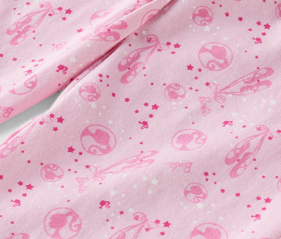 Detailaufnahme eines rosa Stoffes, bedruckt mit Ballettschuhen, Sternen und Barbie-Silhouetten.