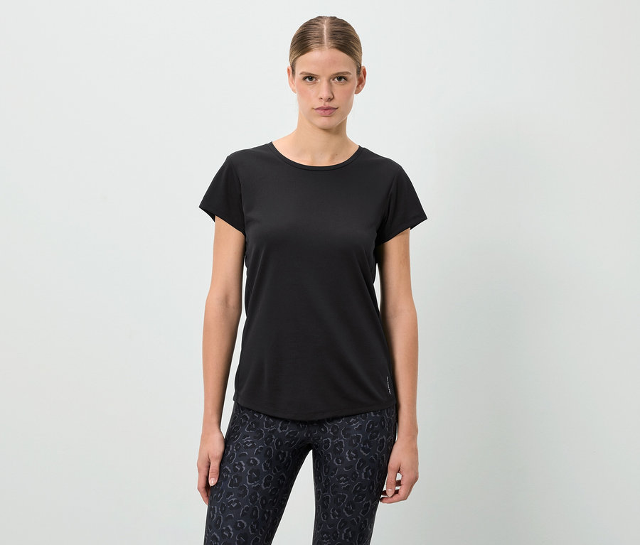 Frau steht und trägt ein schwarzes T-Shirt und gemusterte Leggings.