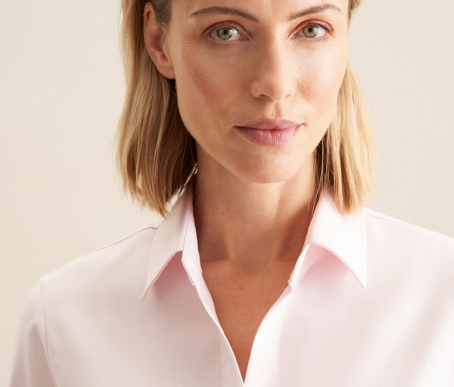 Porträt einer blonden Frau in einer rosafarbenen Seidensticker Twillbluse.