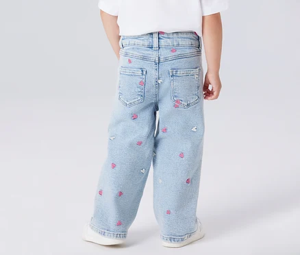 Rückansicht eines Kindes mit hellblauen Jeans mit rosa und weißen Herzaufdrucken.