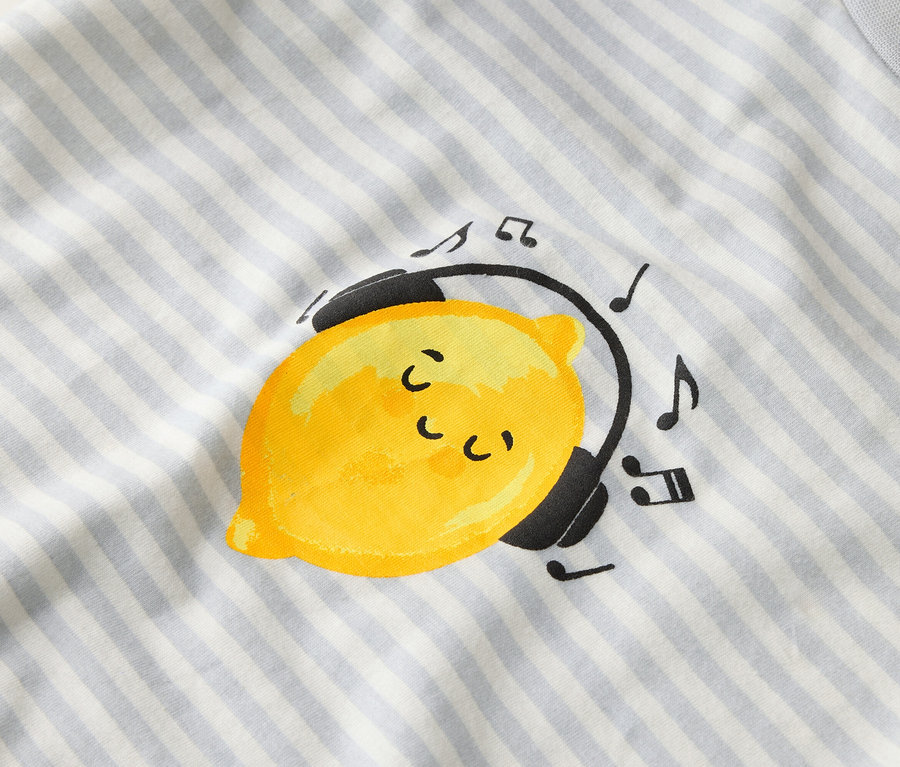 Auf einem gestreiften Stoff ist eine gelbe Zitrone mit Kopfhörern und Noten abgebildet.