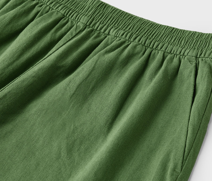 Detailaufnahme einer grünen Hose mit elastischem Bund und Eingrifftasche.