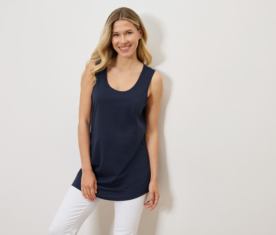 Frau trägt ein marineblaues Tanktop und weiße Jeans.
