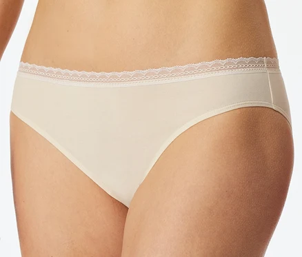 Eine Person trägt einen beigefarbenen SCHIESSER Rio-Slip mit zarter weißer Spitzenborte am Bund.