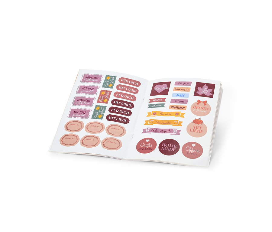 Ein offenes Stickerbuch mit verschiedenen Aufklebern in Rosa-, Rot- und Brauntönen. Die Aufkleber haben Aufschriften wie „MIT LIEBE“, „FÜR DICH“ und „HOMEMADE“.