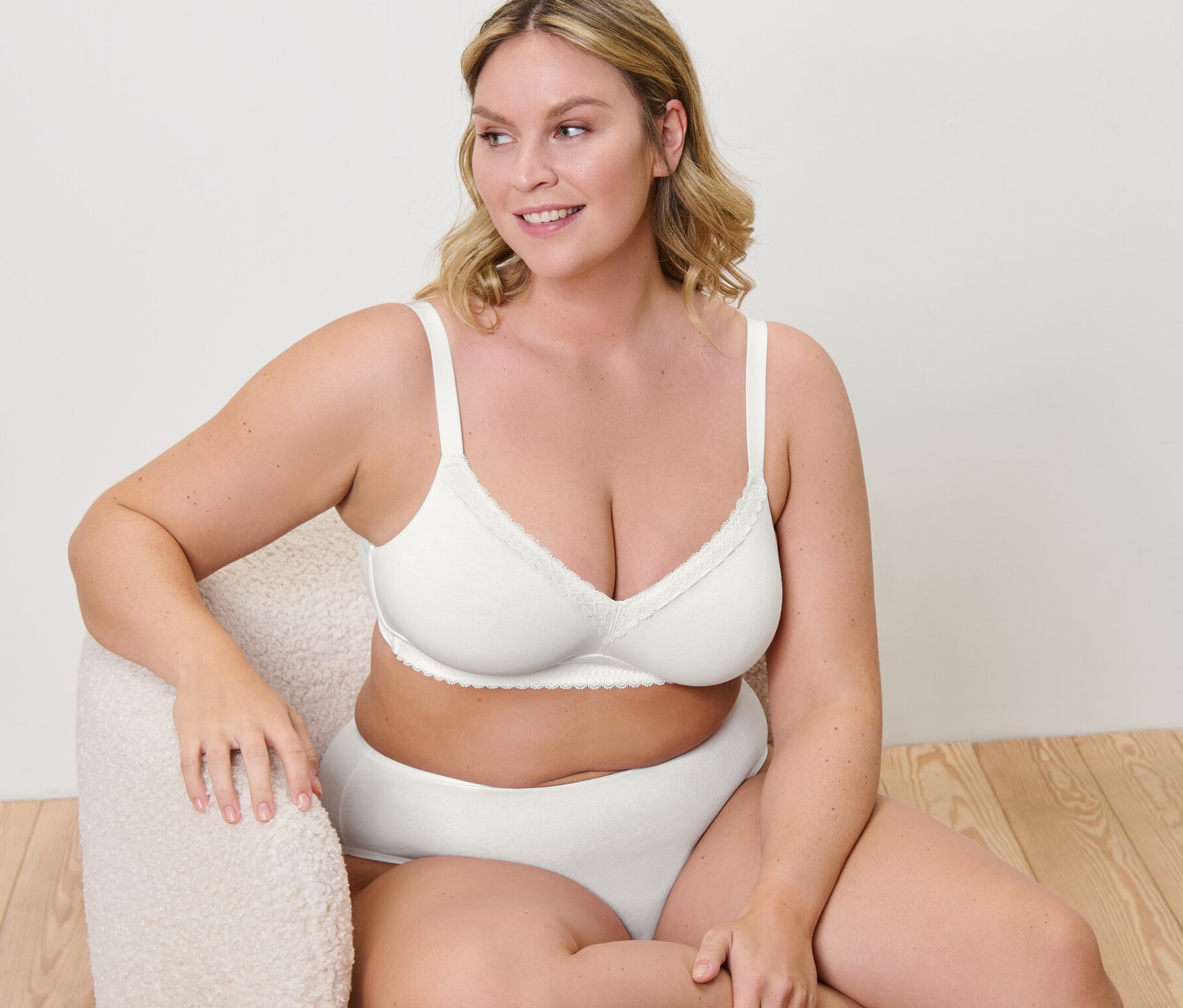 Frau sitzt im Sessel und trägt einen Soft-BH.