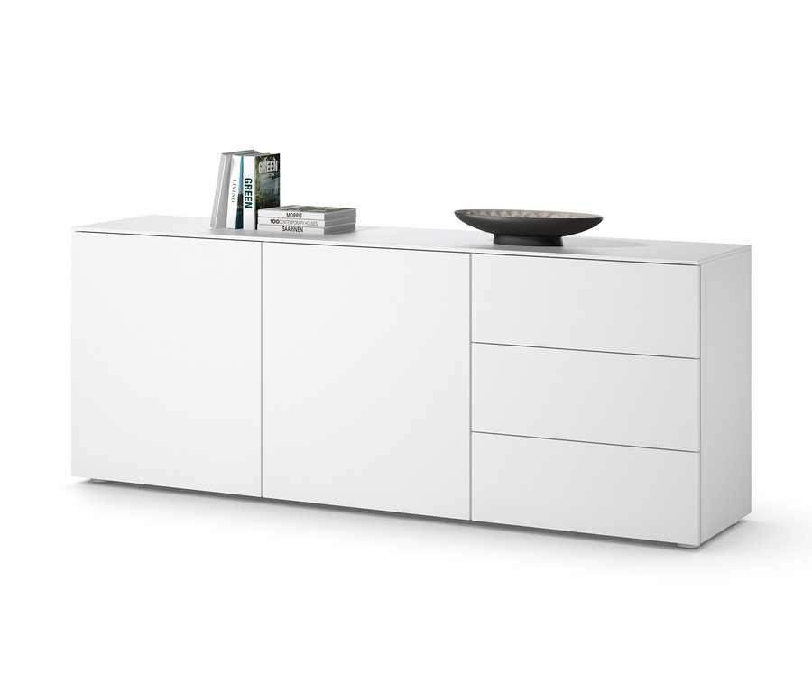 Weißes Sideboard mit drei Schubladen und Türen, auf dem Bücher und eine Schale liegen.