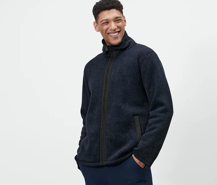 Mann posiert mit Händen in den Taschen in Strickfleece-Jacke.