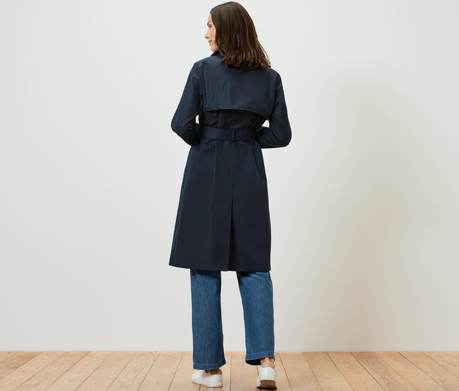 Frau trägt dunkelblauen Trenchcoat.