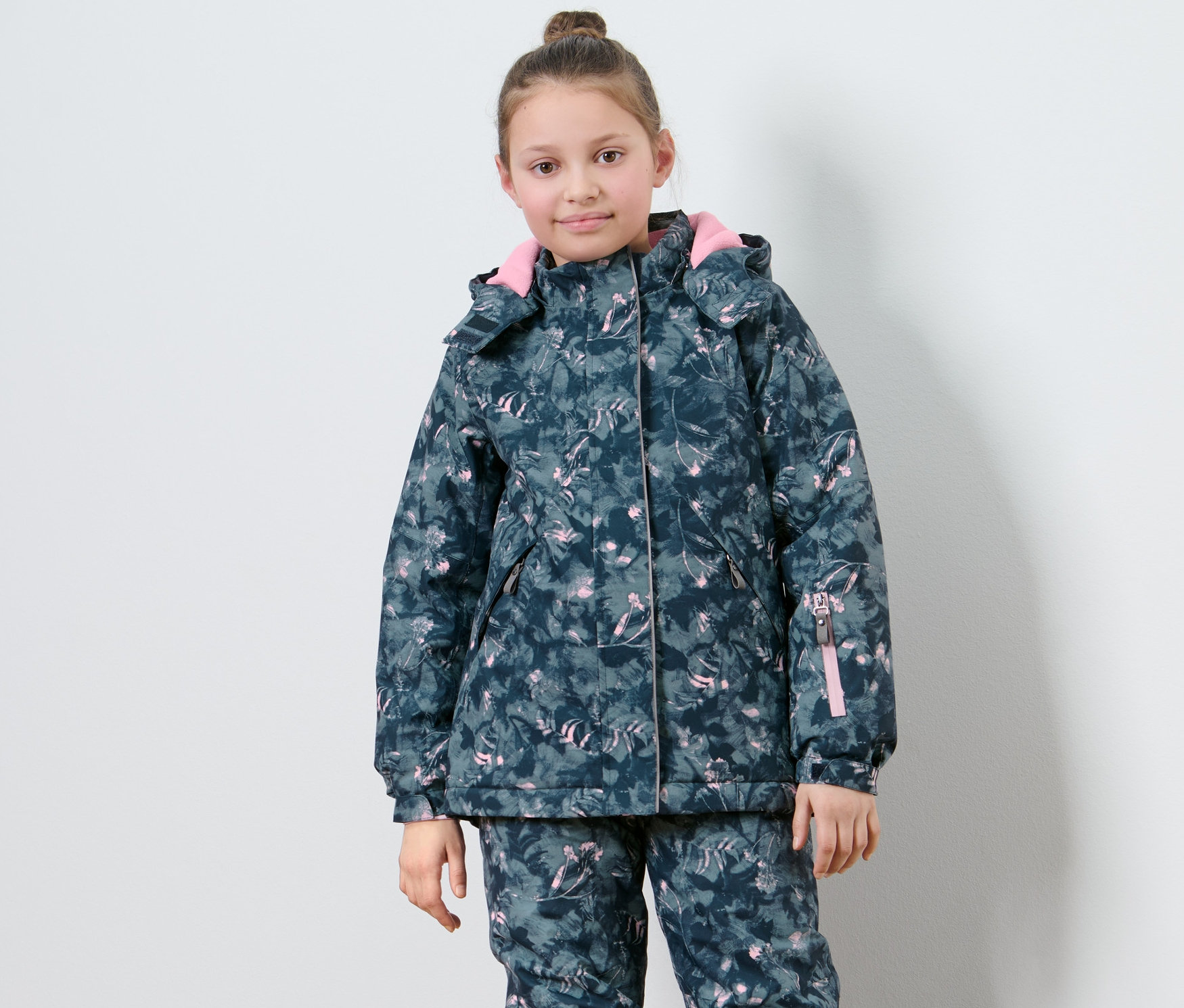 Mädchen posiert in Kinder-Skijacke mit Muster.