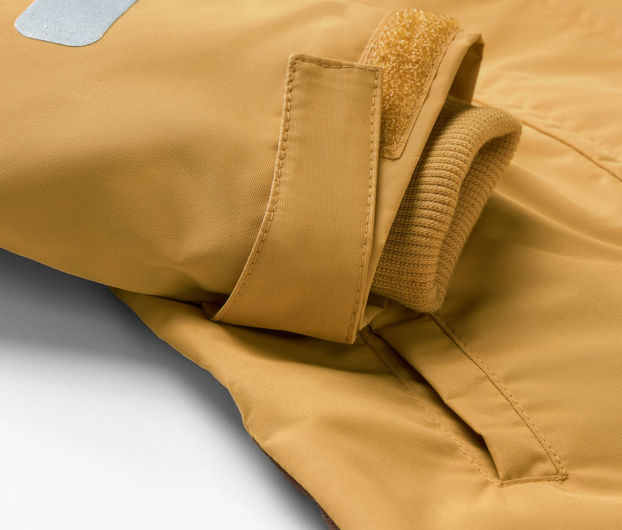 Detailansicht eines Kinder-Regen-Einteilers mit Tasche und reflektierendem Detail.