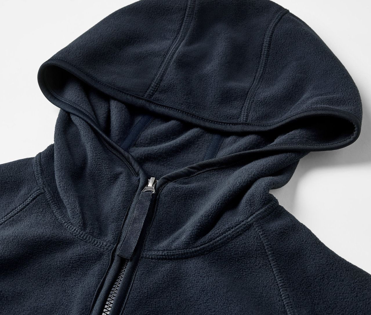 Detailaufnahme einer blauen Fleecejacke mit Kapuze und Reißverschluss.