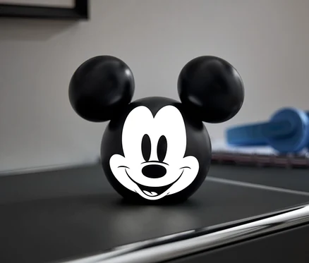 Schwarze Kugel mit weißem Mickey Mouse Gesicht auf einer schwarzen Kommode.